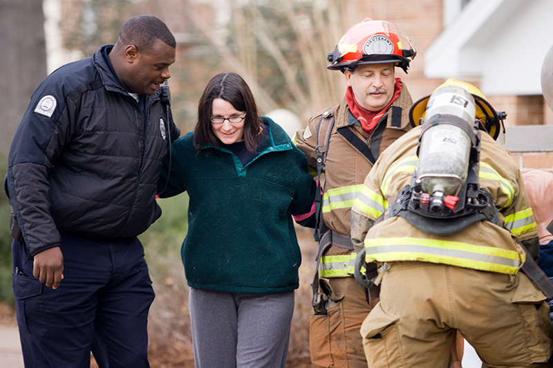 Police and firefighters assisting a volunteer actor during an emergency response training drill.